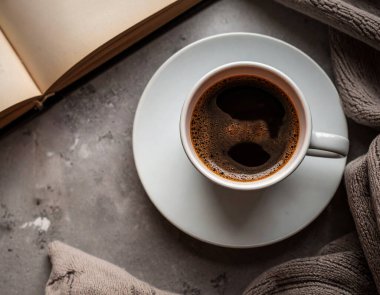 Bir fincan sade kahvenin en üst görüntüsü bir kitapla birlikte taşra masasının üzerinde..