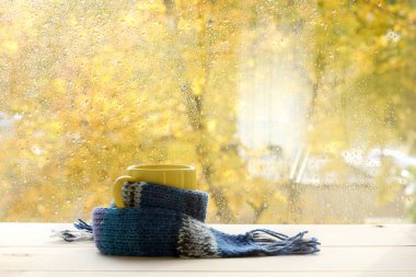 damla yağmur ruh hali ile sonbahar / ısınma çay sonra bir pencerenin önünde bir ısınma fularlı sarı kupa