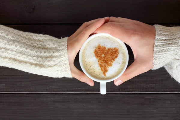 warming cappuccino decorated a symbol heart in hands couple a top view