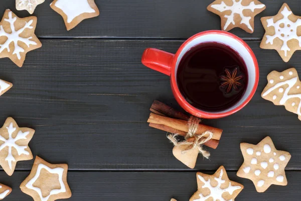 flat layout with red mug filled with a warming drink, surrounded by a shaped cookies top view / tea with a festive aroma