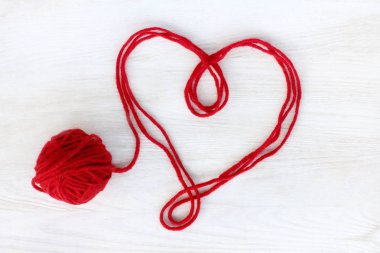 kalp sembolü bir ışık ahşap yüzey üzerinde kırmızı iplik görünümü top / aşk sevgi bağı çözülmüş