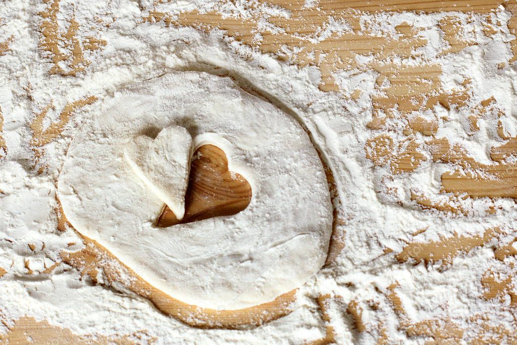 blank heart shape of farinaceous dough on a wooden table / cooking pastry for the holiday