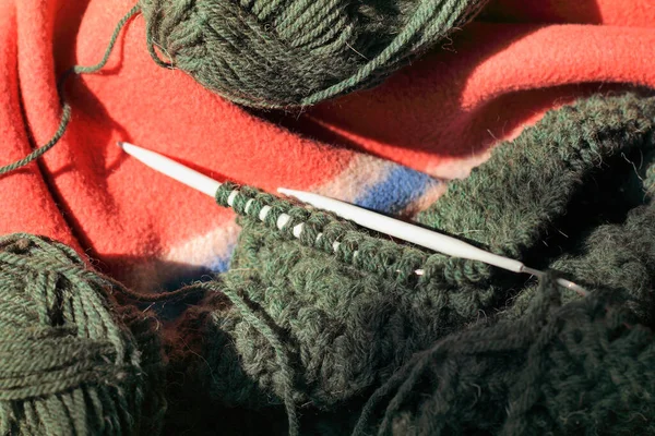 Skeins of wool yarn and knitting needles on a plaid top view / homemade hobby in a cozy setting