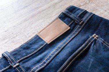 Kahverengi deri etiket ahşap zemin üzerine mavi jeans.