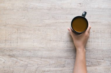 Bir fincan kahve ahşap doku arka planda tutan el.