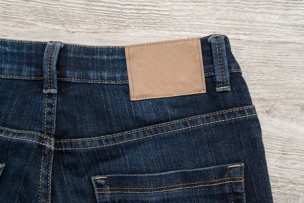 木材の背景とジーンズの背面にブルー ジーンズの茶色の革ラベル — ストック写真