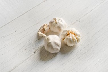 Organik sarımsak bütün ve karanfil beyaz ahşap zemin üzerinde.