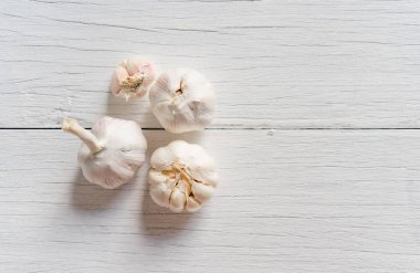 Organik sarımsak bütün ve karanfil beyaz ahşap zemin üzerinde.