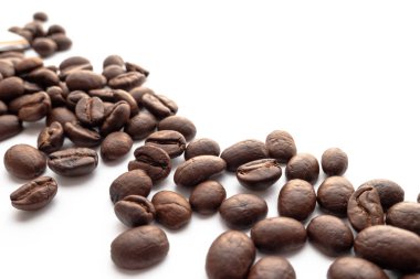 Beyaz zemin üzerine kavrulmuş kahve çekirdekleri. Yakın çekim yansıma.