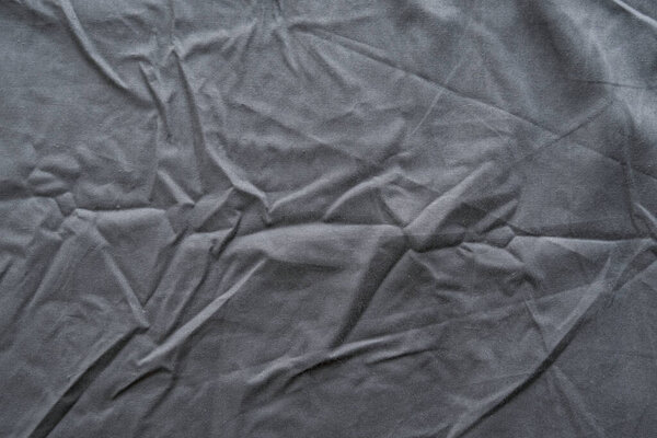 Abstract pattern of a gray crumpled bed sheet in bedroom. Gray wrinkled fabric texture rippled surface, Close up bed sheet in the bedroom after being used.