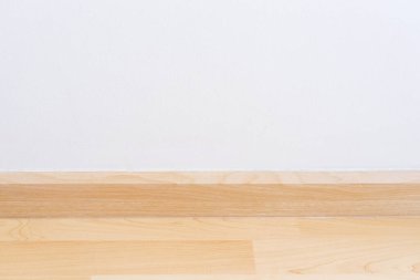 Tahta duvar eteği, ahşap kaplama döşemeli ve beyaz havan topu duvarlı bitiş malzemesi. Beyaz duvarı ve ahşap zemini olan boş oda. Yeni, temiz, modern tasarım..