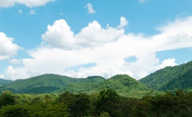 Mavi gökyüzünün altında yeşil dağlar ve güzel gökyüzü bulutları. Doğal arka plan için açık hava manzarası.