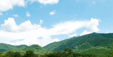 Mavi gökyüzünün altında yeşil dağlar ve güzel gökyüzü bulutları. Doğal arka plan için açık hava manzarası.