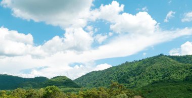 Mavi gökyüzünün altında yeşil dağlar ve güzel gökyüzü bulutları. Doğal arka plan için açık hava manzarası.