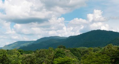 Mavi gökyüzünün altında yeşil dağlar ve güzel gökyüzü bulutları. Doğal arka plan için açık hava manzarası.