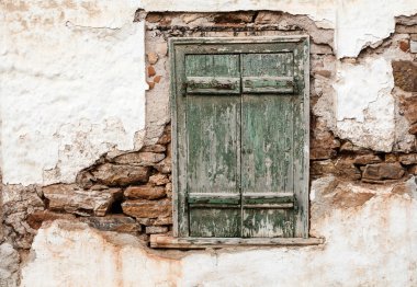 Yıpranmış duvarda yeşil panjurlar ile eski ahşap pencere.