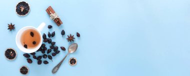 Yabani gül çay demlendi ve kurutulmuş tohumları, mavi arka plan ile ilgili nesneleri yığını.