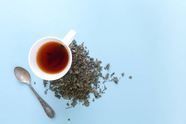 Taze demlendi yeşil çay ile mavi arka plan üzerinde kurutulmuş yaprakları yığını.