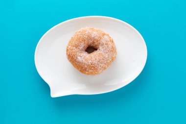 Mavi arka plan üzerinde metin kabarcık şeklinde plaka üzerinde şeker kaplı çörek.