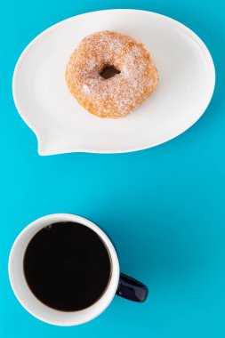 Bir fincan kahve ve çörek mavi zemin üzerine metin kabarcık şeklinde plaka üzerinde.