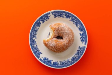 Çörek şeker süslemeli, mavi zemin üzerine beyaz yuvarlak tabakta ile kaplı.