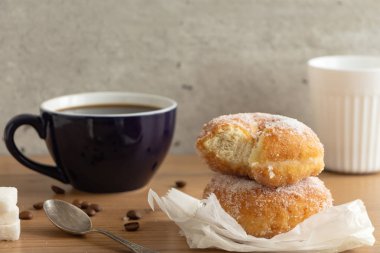 Şeker kaplı çörek ile iki bardak kahve, ahşap masa üzerinde buruşuk Kağıt üzerinde.