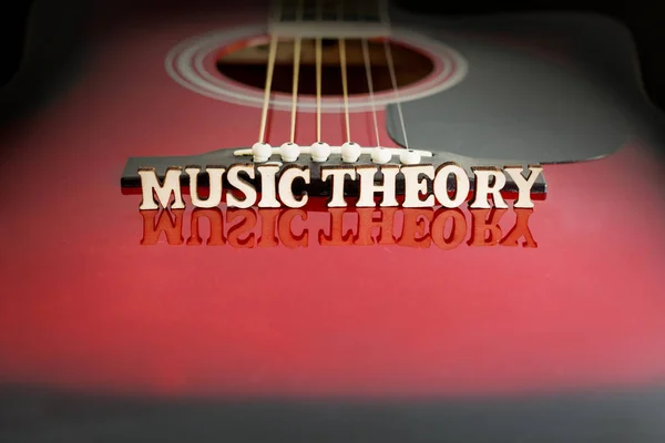 Ord Rock Musik med träbokstäver, på reflekterande yta av en akustisk gitarr. Gitarrernas broperspektiv. Kreativ bakgrund. Stockbild