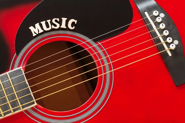 Μουσική λέξη με ξύλινα γράμματα, κοντινό στην επιφάνεια της κόκκινης ακουστικής κιθάρας. Φόντο μουσικής ψυχαγωγίας. — Φωτογραφία Αρχείου