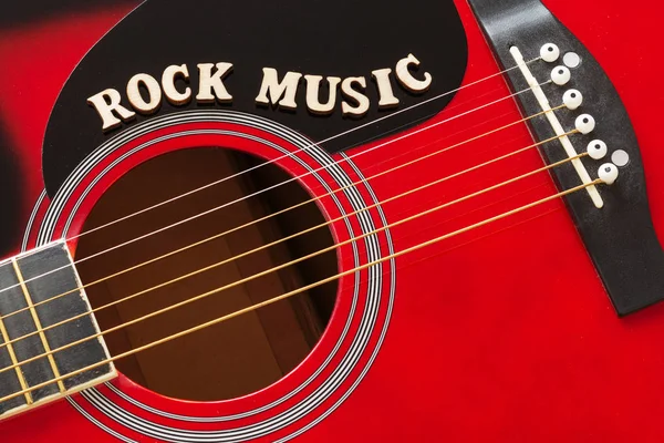 Palavras Rock Music com letras de madeira, close-up em uma superfície de guitarra acústica vermelha. Música entretenimento fundo . — Fotografia de Stock