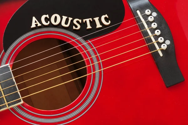 Word Acústica con letras de madera, primer plano sobre una superficie de guitarra acústica roja. Fondo de entretenimiento musical . — Foto de Stock