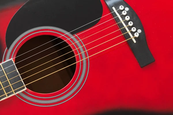 Closeup of a six stringed red acoustic guitar. Music entertainment background.
