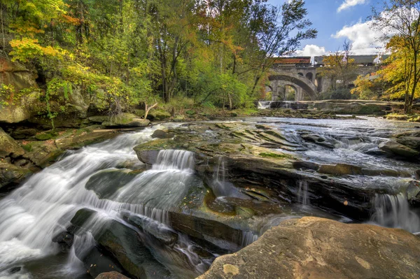 Berea Falls Ohio during peak fall colors. This cascading waterfall looks it's best with peak autumn colors in the trees. The stone arch train bridges make for a nice background.