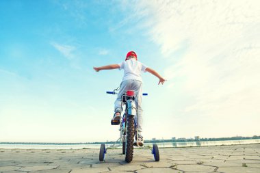 Çocuk bir bisiklet ile Rıhtımlar üzerinde gidiyor.