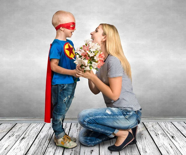 Syn Kostium Superbohatera Daje Matka Bukiet Kwiatów — Zdjęcie stockowe