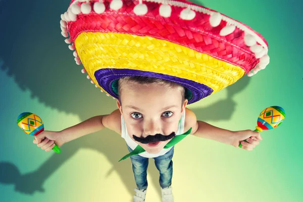 Mexican party.Boy with a fake mustache in a sombrero playing the maracas.