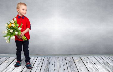 Şık küçük çocuk bir buket bahar Lale tutar. Bahar, tatil, çocuk moda.