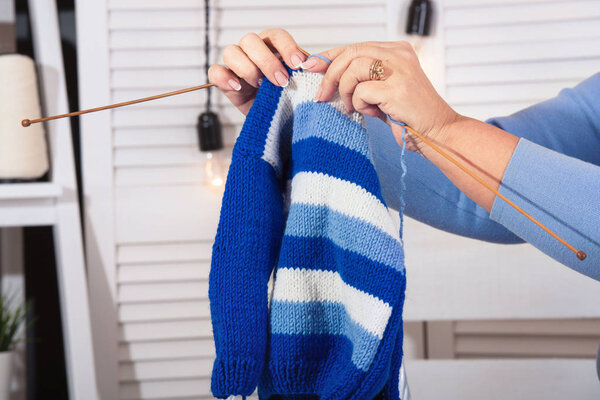 Женские руки вязали свитер вязальными спицами. Хобби
.