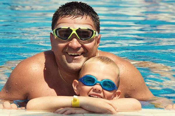 Father and son swimming in the pool at summer day. Leisure and swimming at holidays.