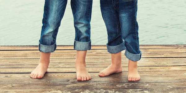 Two brothers stand barefoot on the wooden pier .Family vacation on the lake.