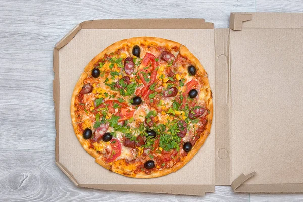 Tasty Italian pizza in the box on a wooden table.Delivery of pizza.Top view. Copy space.