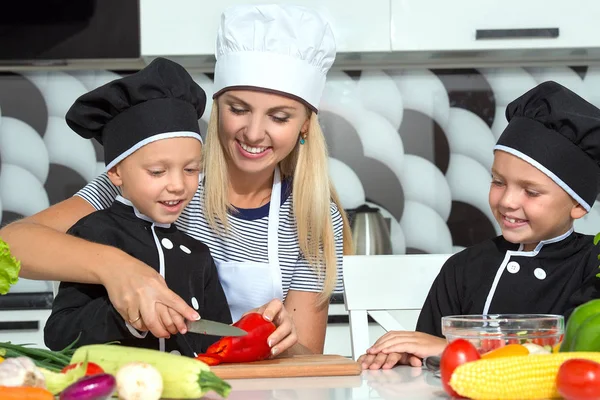 A family of cooks.Healthy eating. Happy family mother and children prepares vegetable salad in kitchen