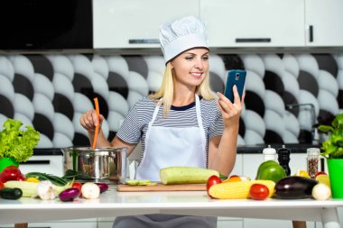 Genç kadın mutfakta yemek. Bir kız bir cep telefonuna bir tarifi okuyor. Sağlıklı gıda diyet. Sağlıklı bir yaşam tarzı. Evde yemek.