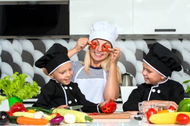 Bir aşçı ailesi. Sağlıklı beslenme. Mutlu aile anne ve çocukları mutfakta sebze salatası hazırlıyor.
