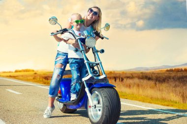 Anne ve oğlu motosiklete biniyor..