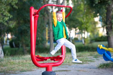 Bir çocuk sokakta simülatörler üzerinde egzersiz yapar. Aktif yaşam tarzı..