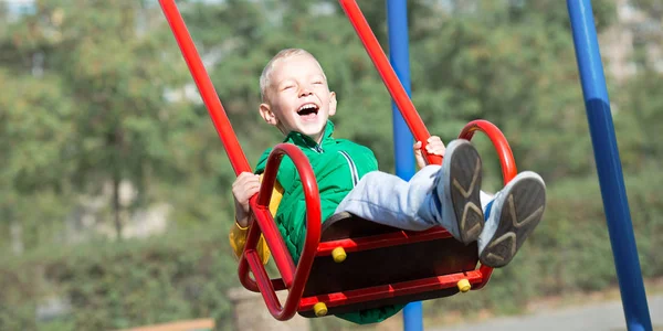 A boy is riding on a swing. A happy weekend.