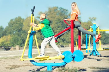 Anne ve oğlu sokaklarda simülatörler üzerinde egzersiz yapıyor. Aktif yaşam tarzı..