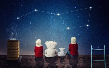Two brothers sit at night on the roof with toy bears and look at the constellation Ursa Major. clipart