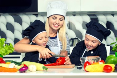 Bir aşçı ailesi. Sağlıklı beslenme. Anne ve çocuklar mutfakta sebze salatası hazırlıyor..