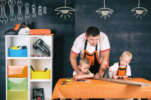 Father and two sons working in the carpentry workshop.